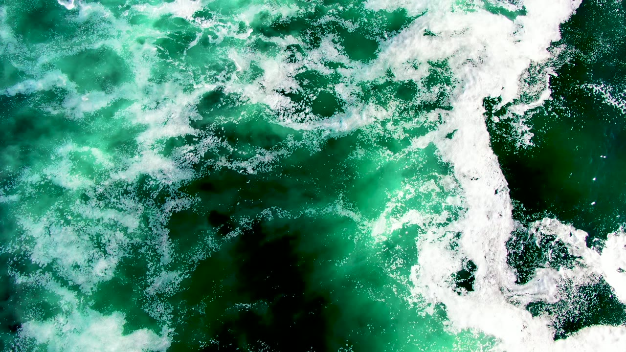 Overhead view of green ocean water and white foam near La Bocana, Baja California Sur, with no visible people.