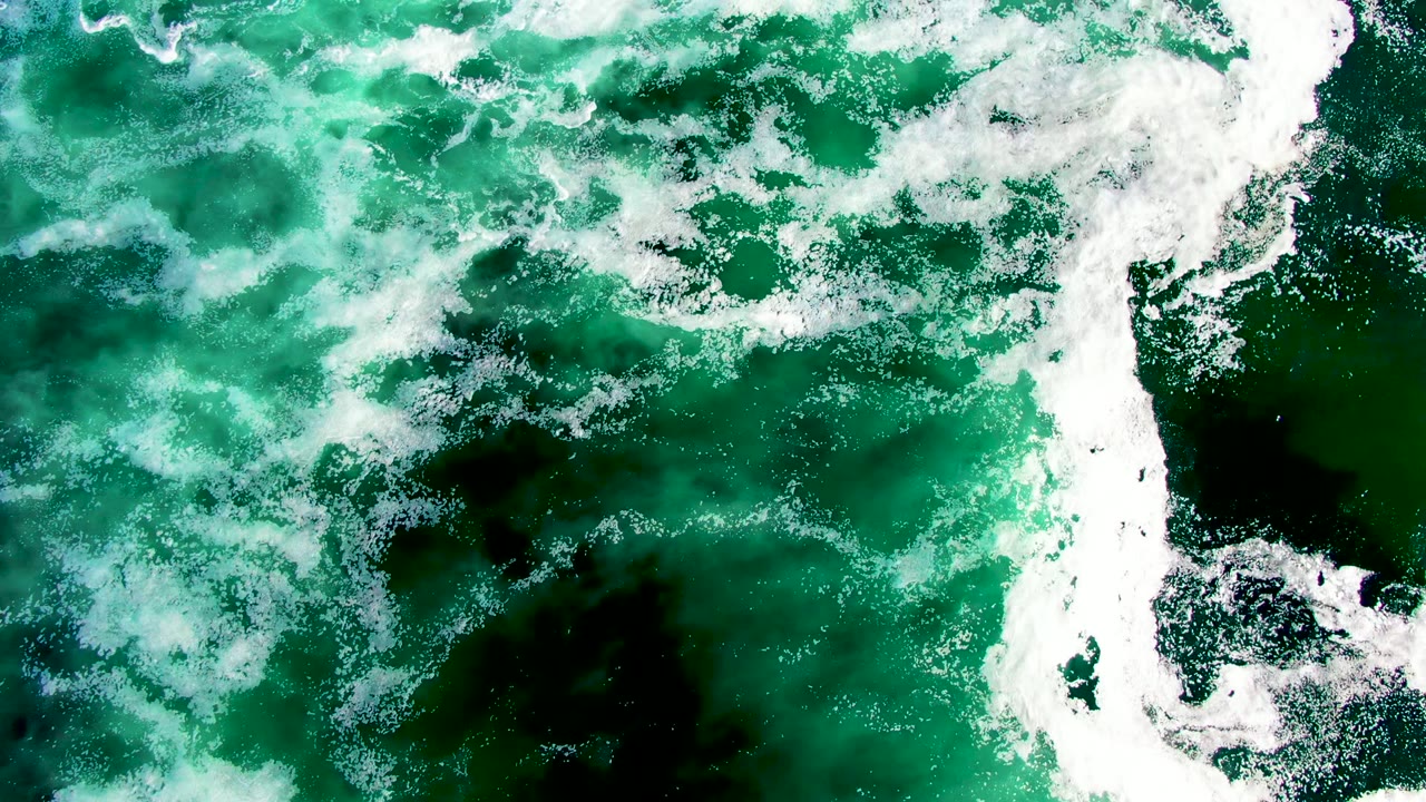 White foam streaks across green ocean surface.