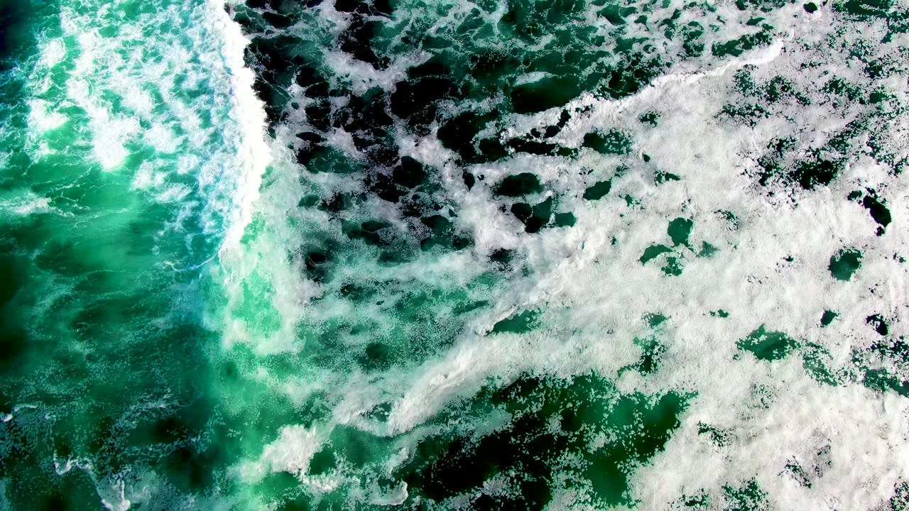 White foam drifting over green ocean water