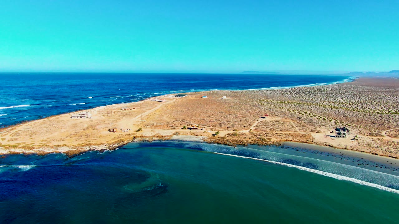 Drone view of surf wrapping along a desert shoreline.