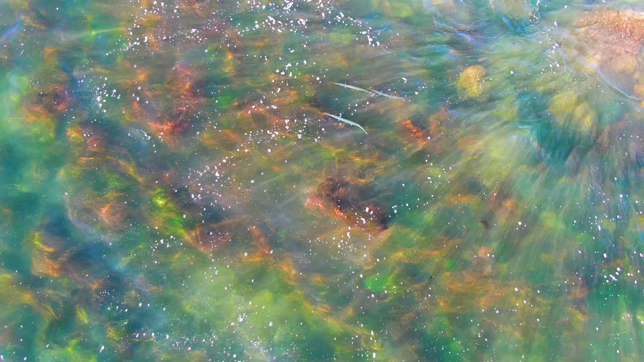 Ripples and bubbles crossing shallow water above rocks
