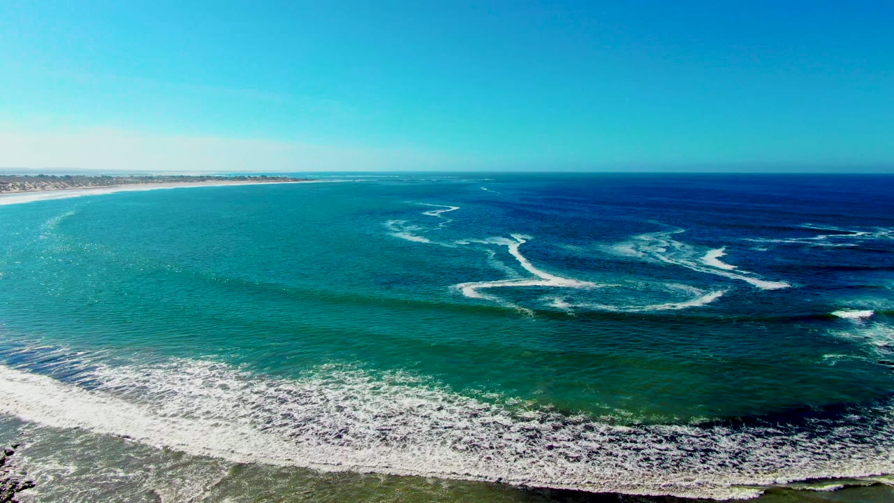 White foam patterns spread across turquoise water near the shore.