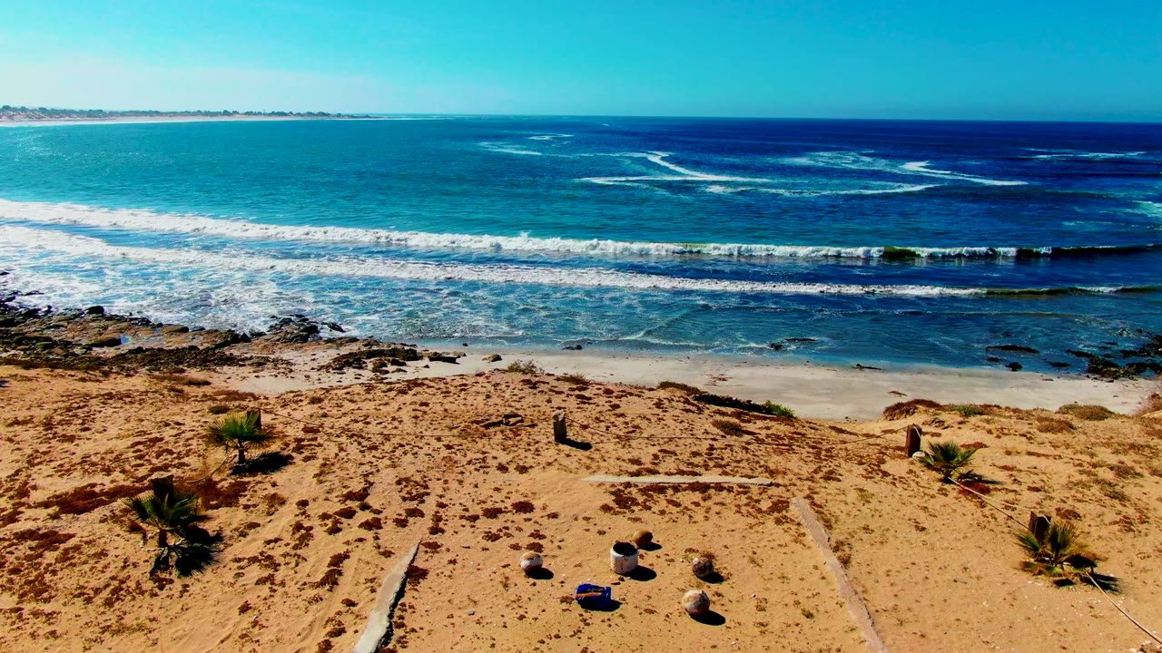 Beach sand and surf with a small bordered sandy area in the foreground.
