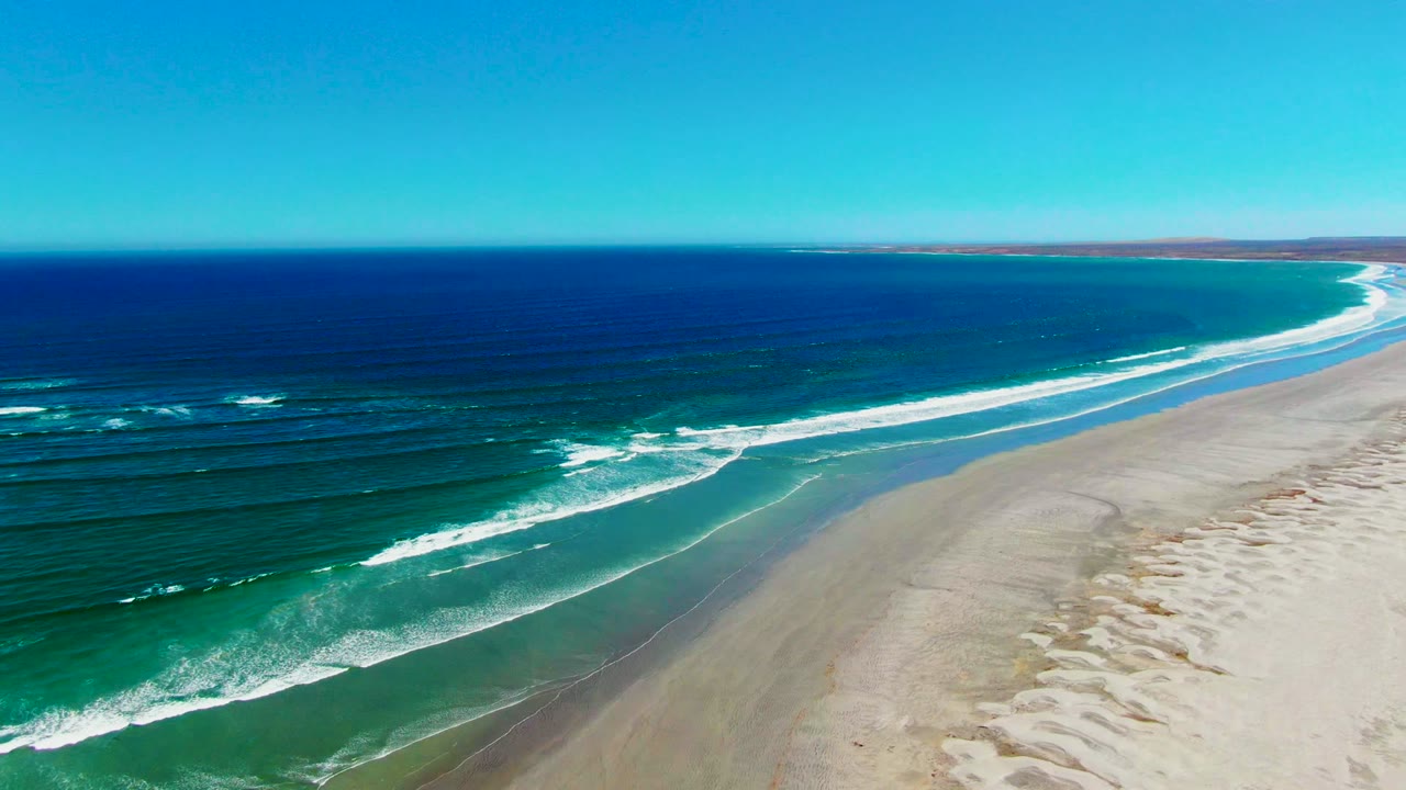 White surf lines rolling onto a broad empty beach