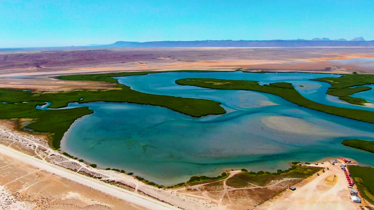Drone view across turquoise reservoir channels and green shoreline vegetation.