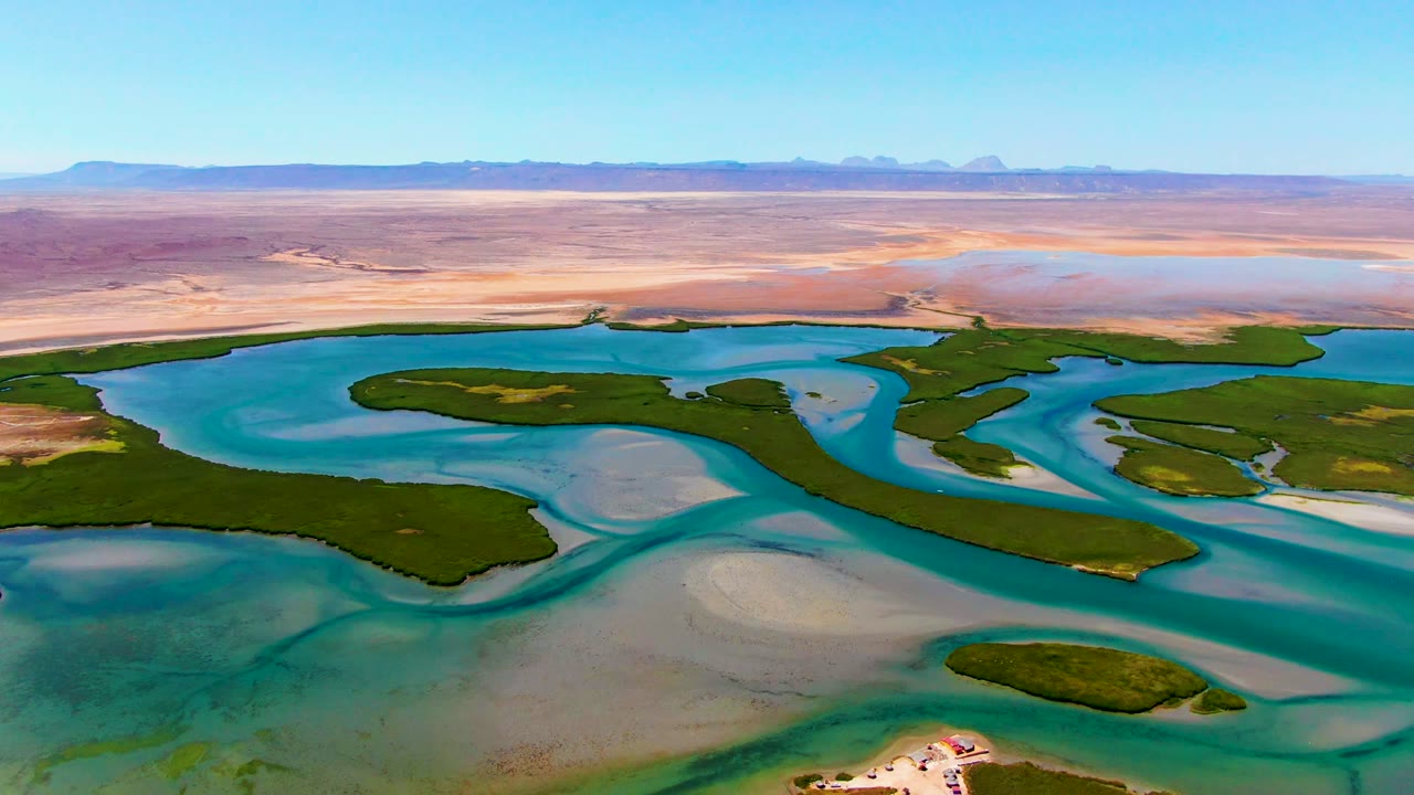 Wide aerial lagoon with curved blue water, green vegetation, and sandy flats.