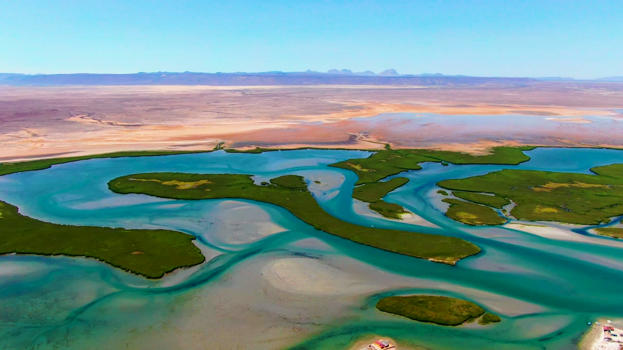 Aerial lagoon channels, green islands, sandbars, and desert horizon.