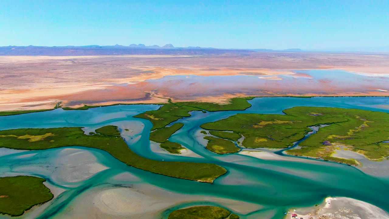 Wide drone view of blue water channels cutting through green coastal land.