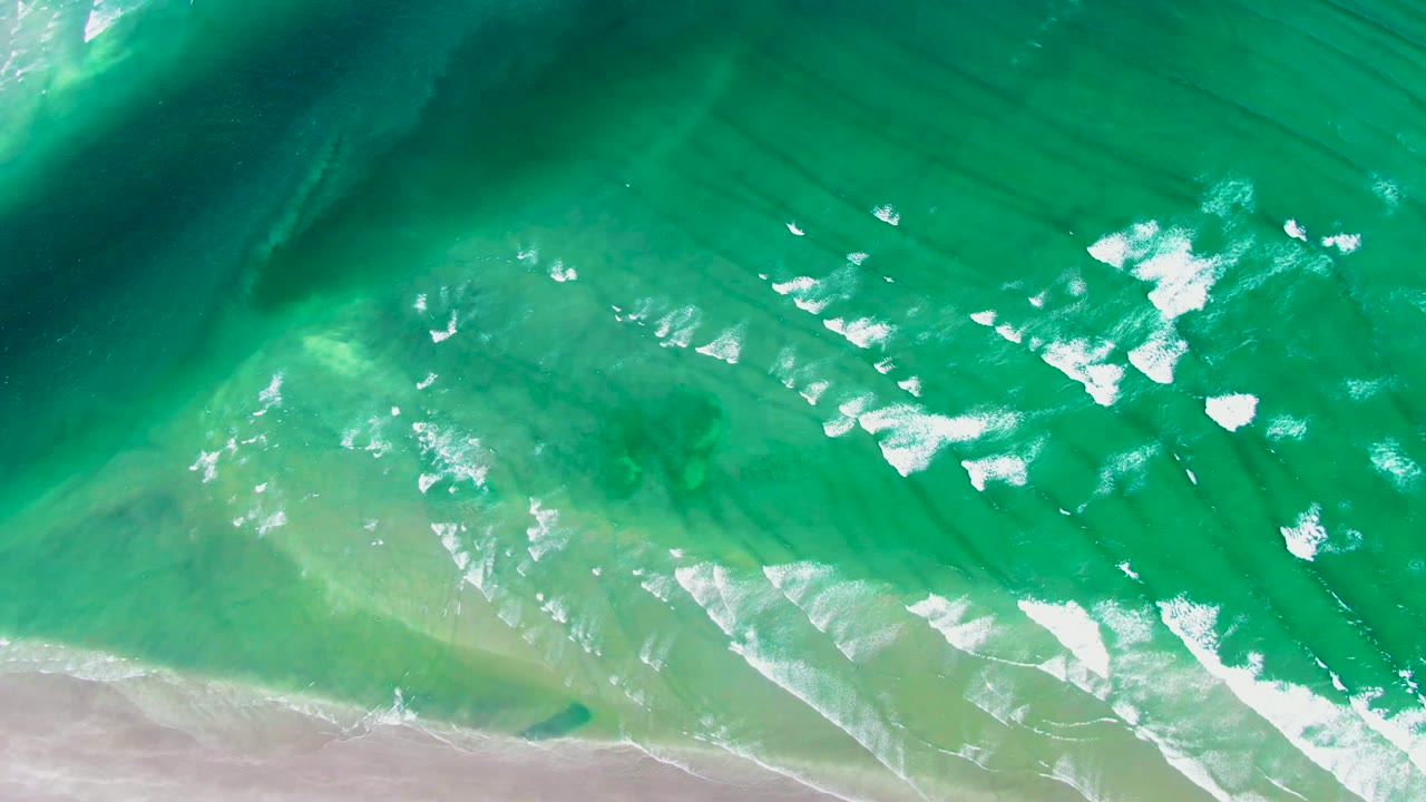 At 0:00, an overhead view at La Bocana shows turquoise water, white foam patches, darker submerged bands, and a sandy beach edge with no visible people.