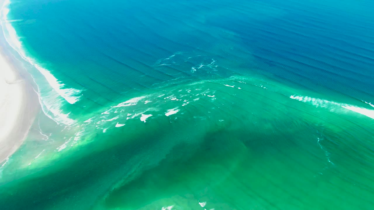 White sand beach beside turquoise water with thin wave foam.