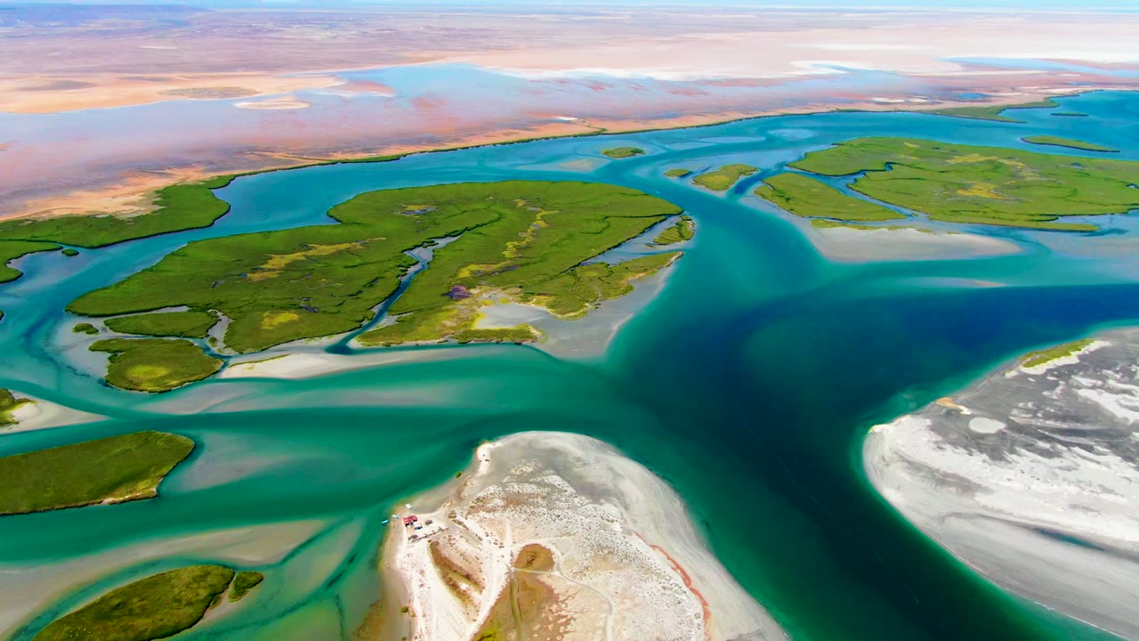 High aerial view of blue water curving between green islands and white sand.