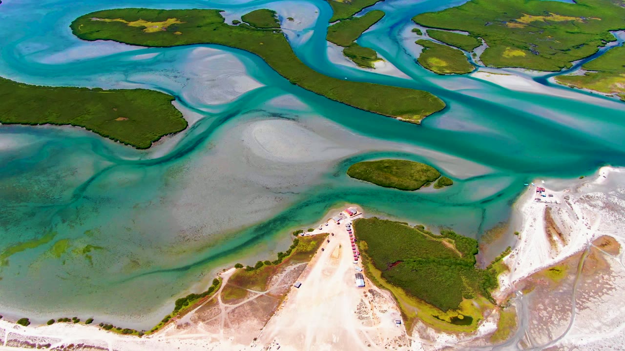 Drone view of shallow coastal water winding between green islands.