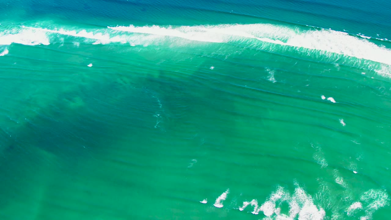 Direct overhead view at La Bocana with a breaking wave rolling across the top of the frame and turquoise water filling the rest, no visible people.