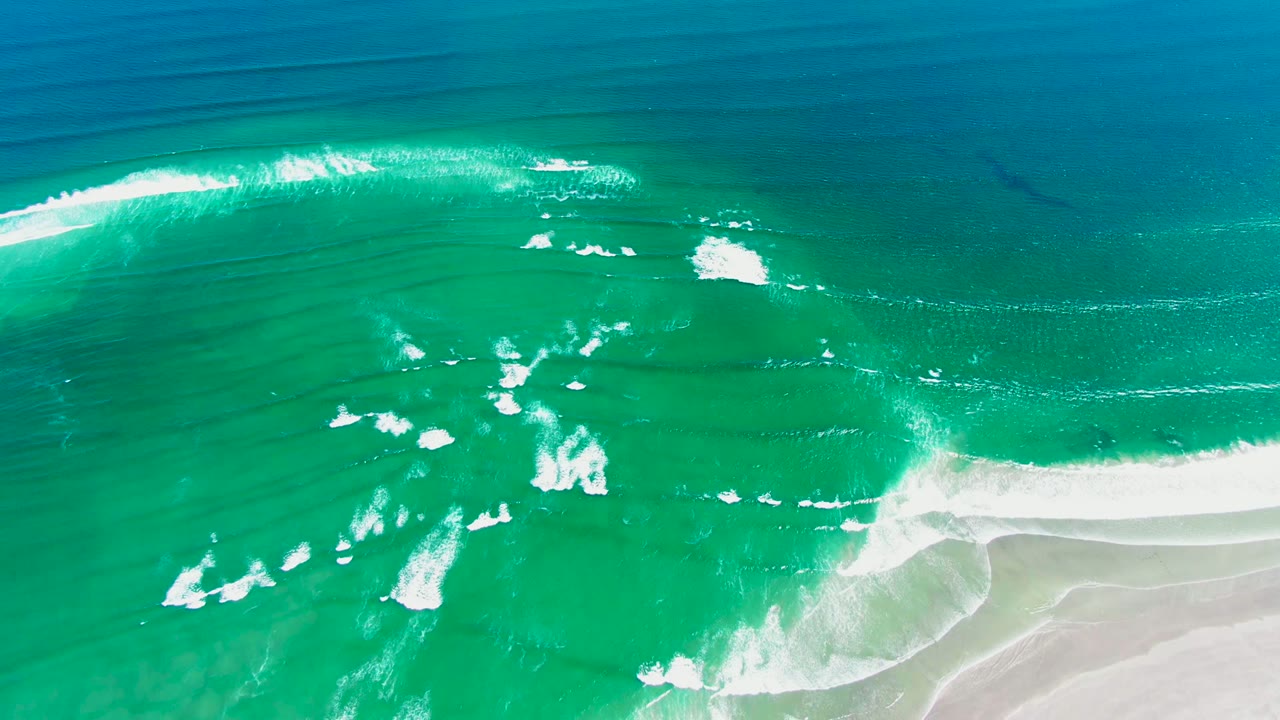 White foam patches spread across turquoise surf by shore