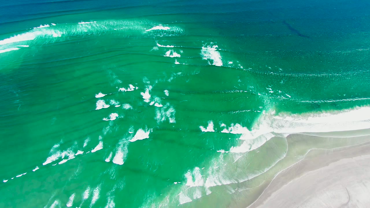 White foam bands breaking across turquoise water near shore