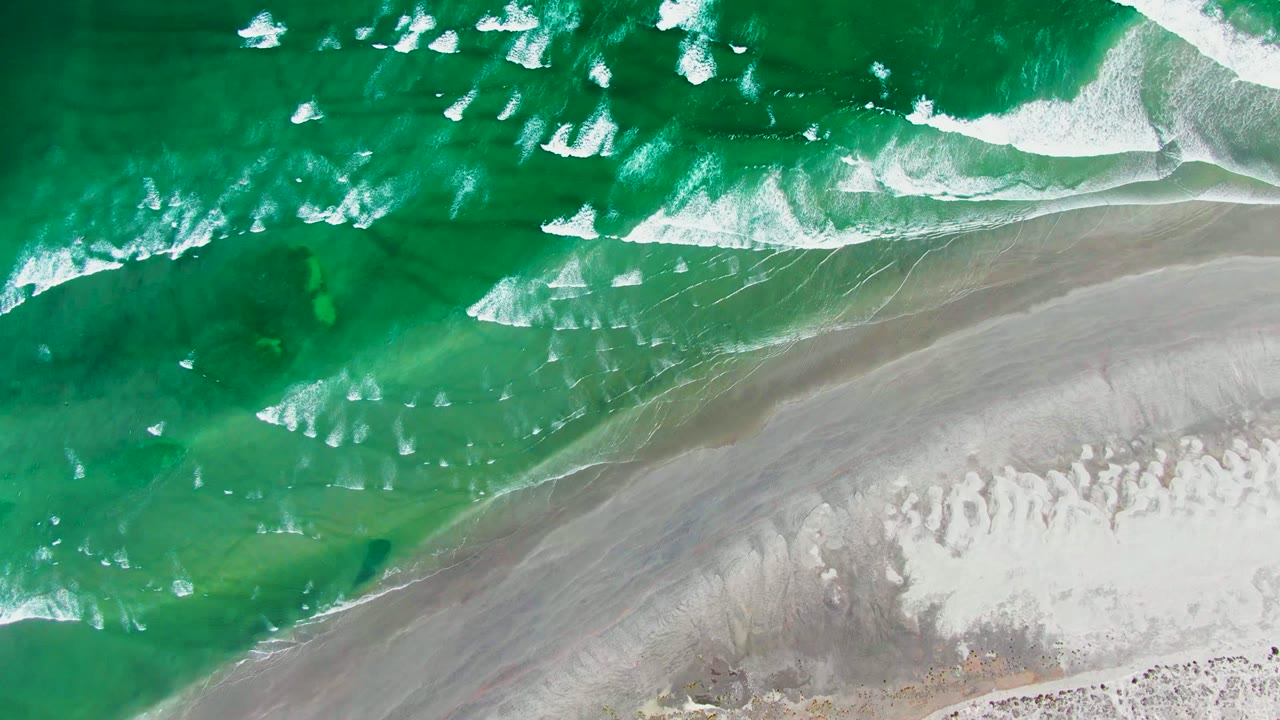Turquoise waves crossing wet beach sand