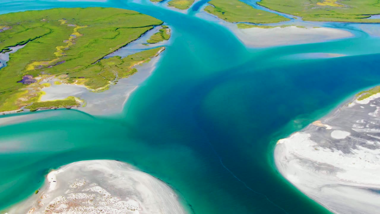 Aerial frame over La Bocana, Baja California Sur, showing turquoise shallows, deep blue water, pale sandbanks, green shoreline, and no visible people.
