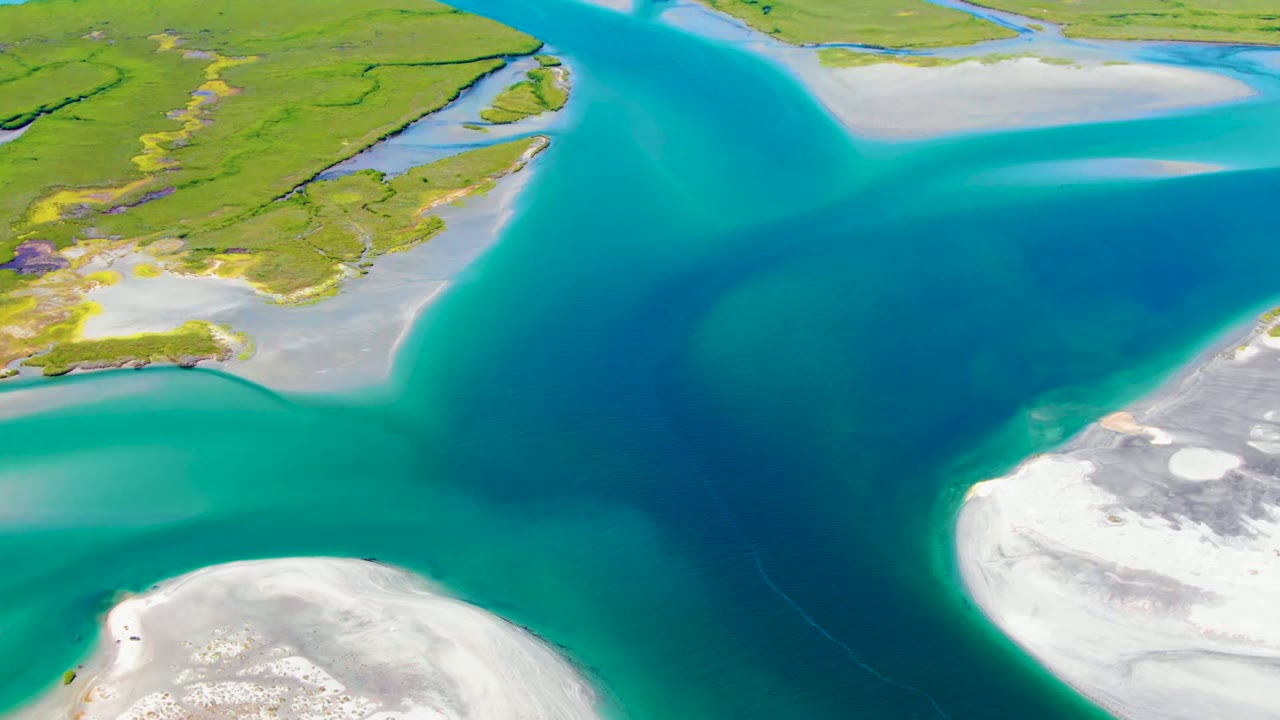 Aerial view over La Bocana, Baja California Sur showing turquoise water, green islands, pale sandbars, and no visible people at the opening frame.