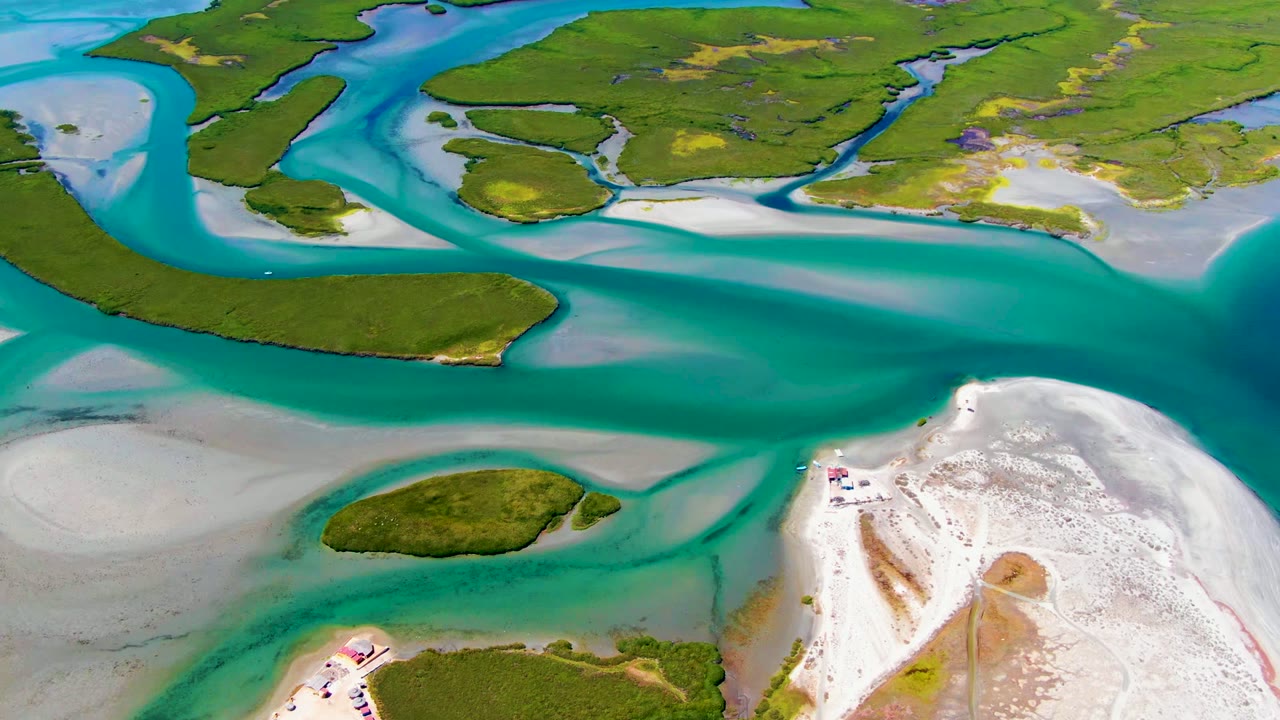 High aerial view over La Bocana, Baja California Sur, with turquoise water crossing between green islands and white sand flats, no visible people.