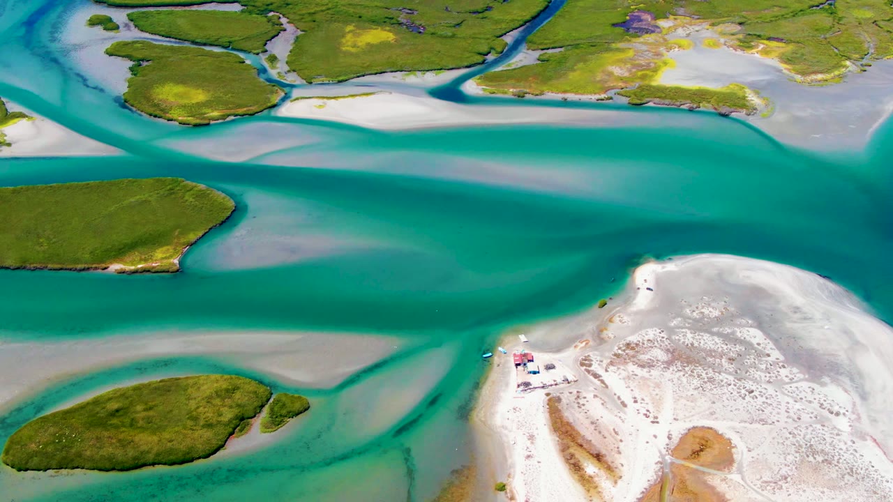 Turquoise water curves around green islands beside a pale beach.