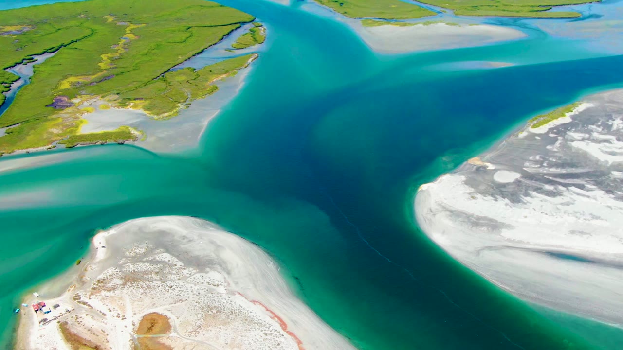 Aerial view over La Bocana, Baja California Sur, showing turquoise delta water between white sandbanks and green wetland islands, with no visible people.