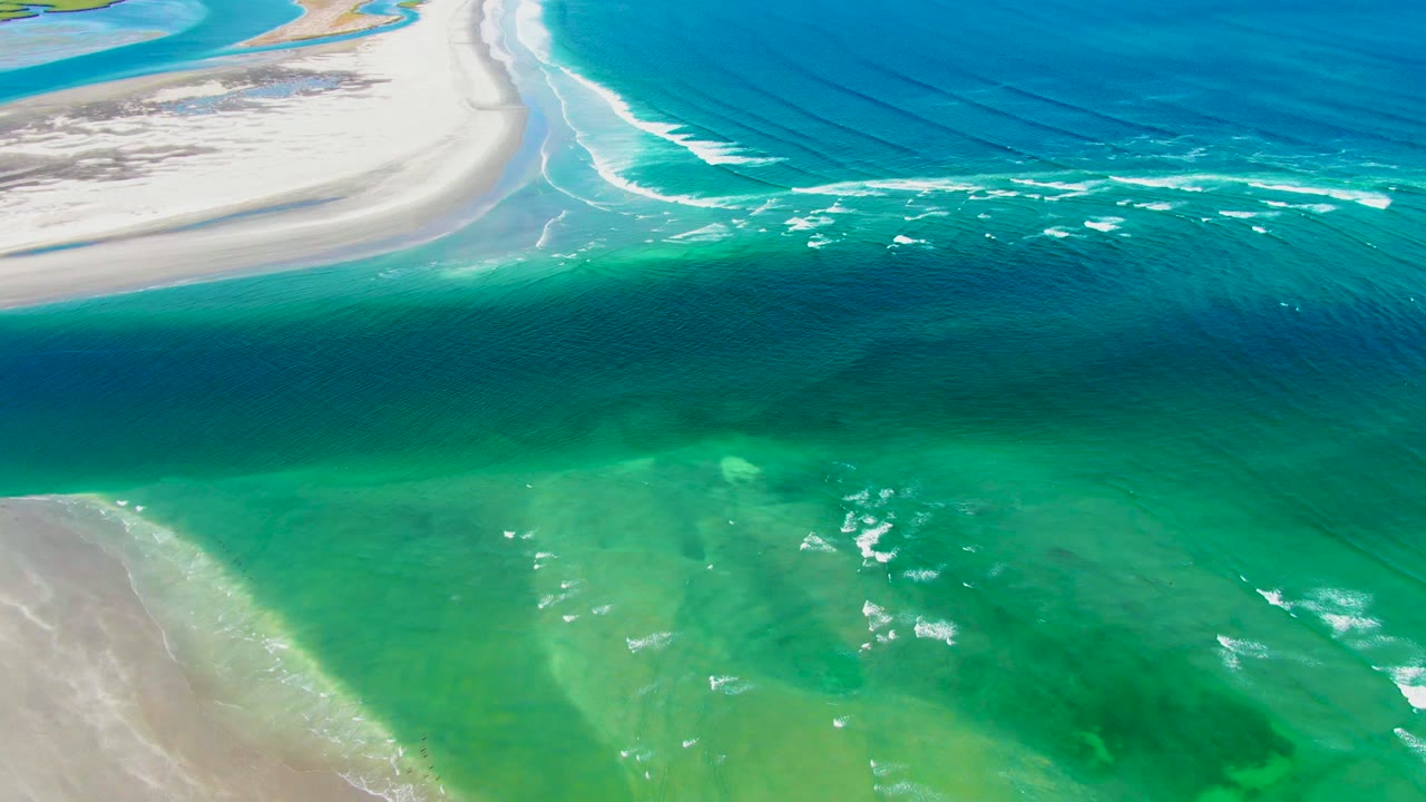 Pale beach and turquoise ocean with small whitecaps.