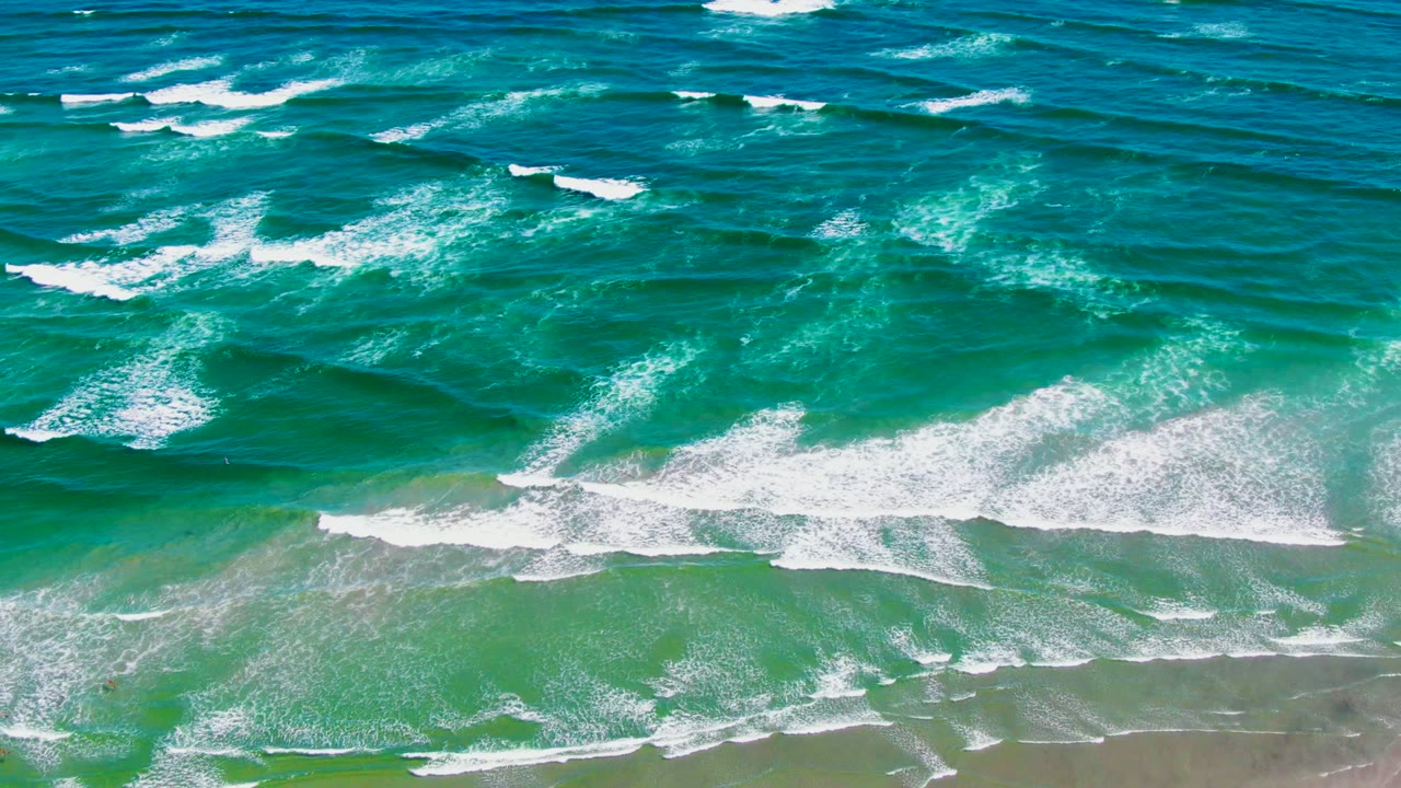 White surf bands spread across turquoise water near shore.