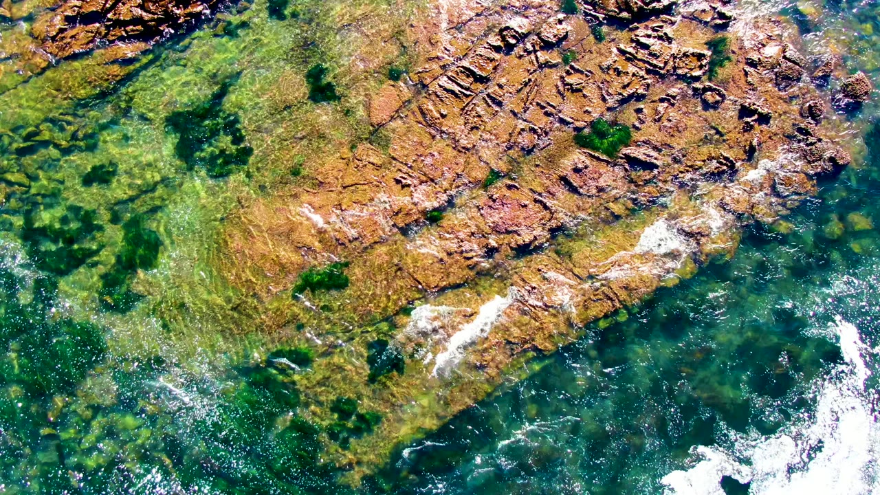 Rock shelf and shallow green water with foam along the edge