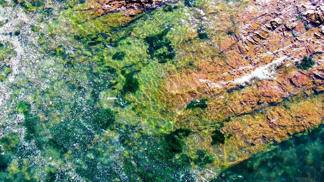 Rippling green water crossing submerged rock shelves