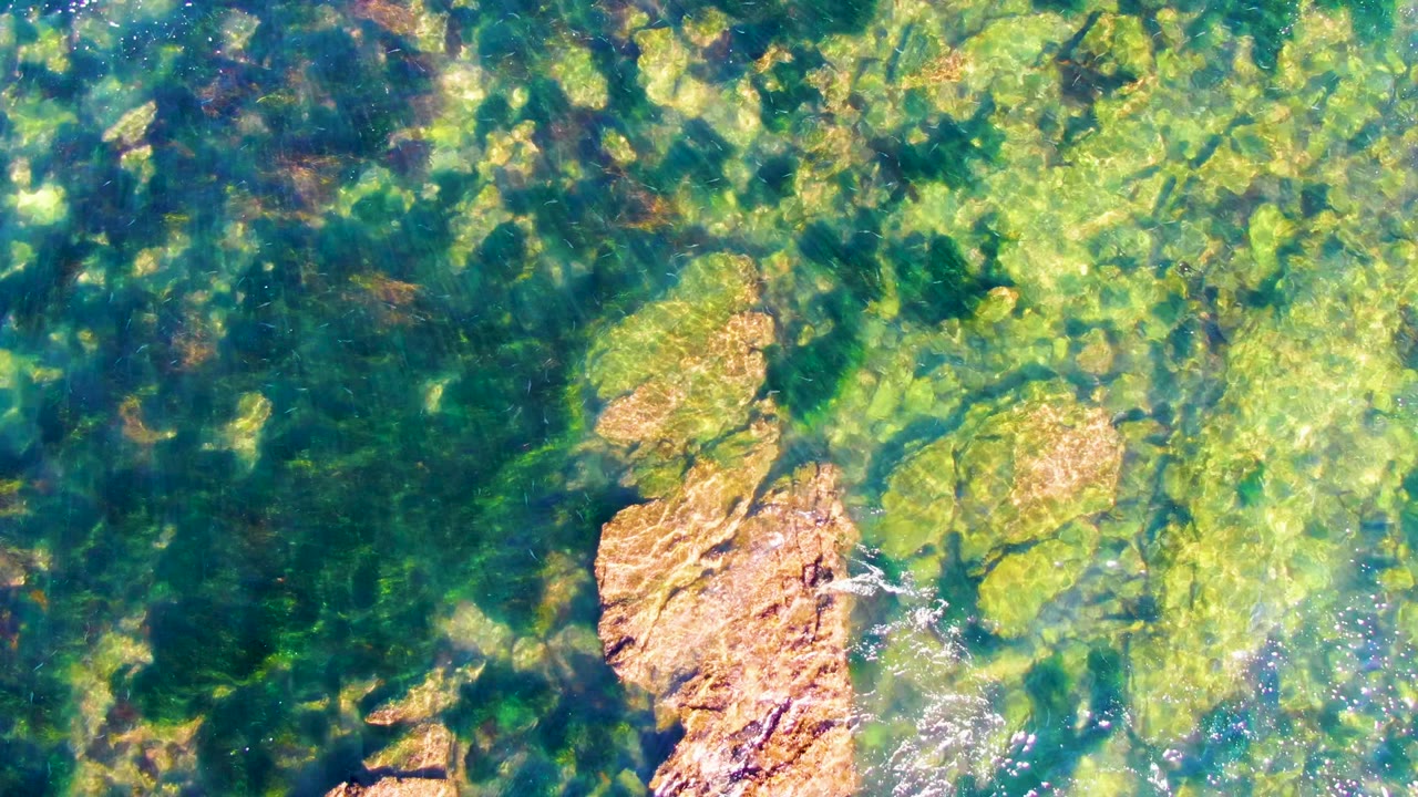 Sunlit rocks under rippled green water