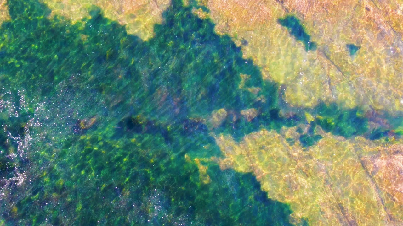 Smoke crossing green vegetation and light farmland from above.
