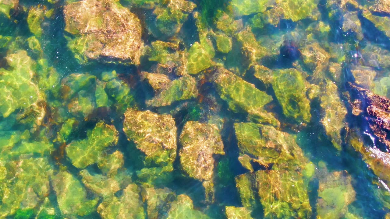 Sunlit ripples crossing submerged coastal rocks