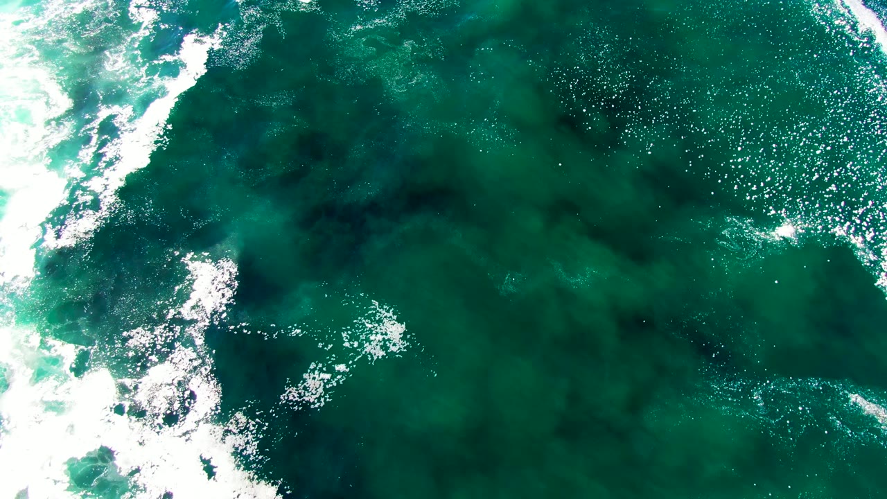 Aerial ocean surface with foam streaks and sunlit ripples