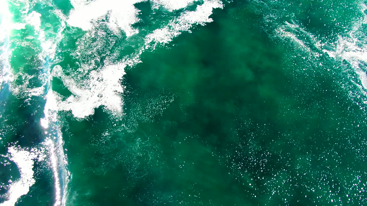 White wave foam spreading over green ocean water