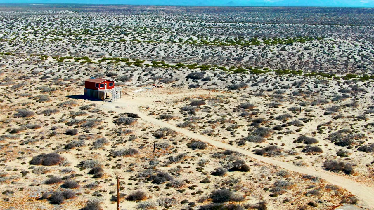 Red building beside sandy roads in desert scrub.