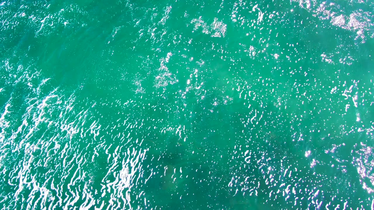 Overhead view of turquoise ocean water at La Bocana, Baja California Sur, with dense ripples and bright reflections near the start of the clip, no visible people.