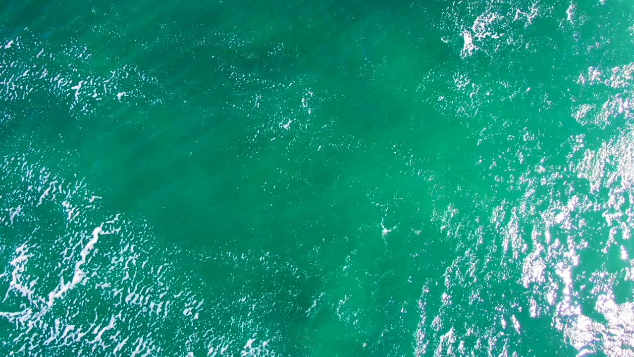 Blue-green water surface with small wave texture and scattered foam