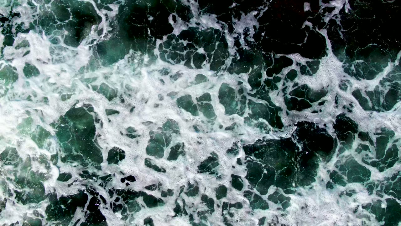 Foamy surf drifting across green ocean water