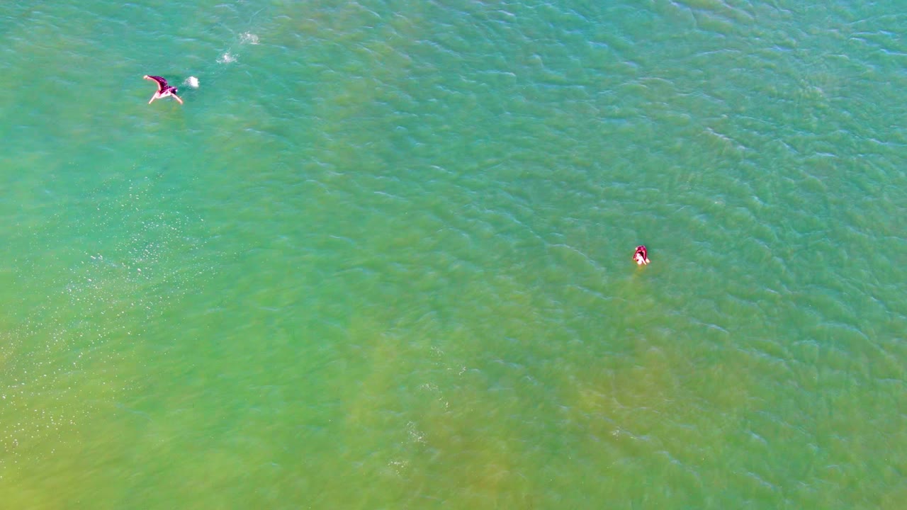 Overhead swimmers with a bright splash in clear green ocean water.