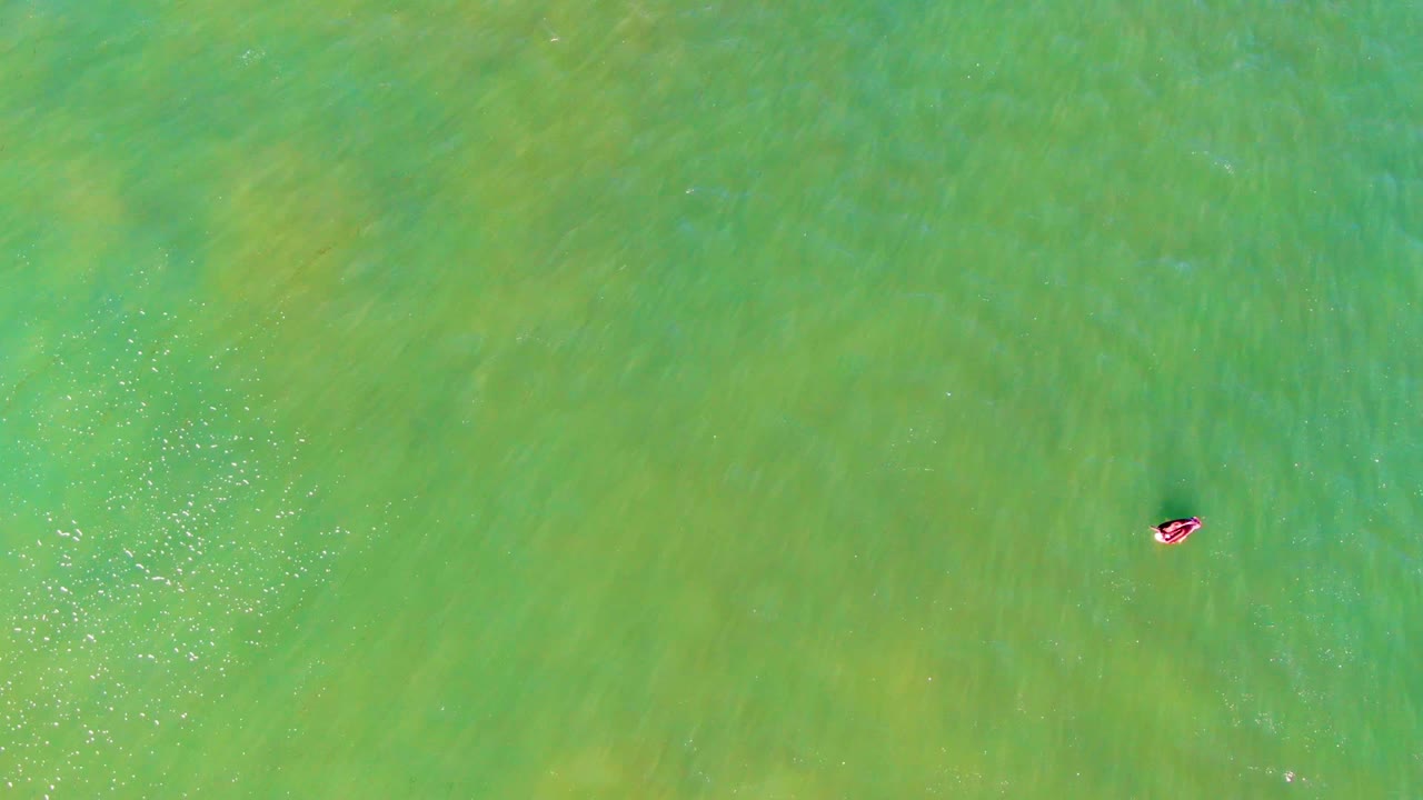 Swimmer low in frame amid green water ripples.