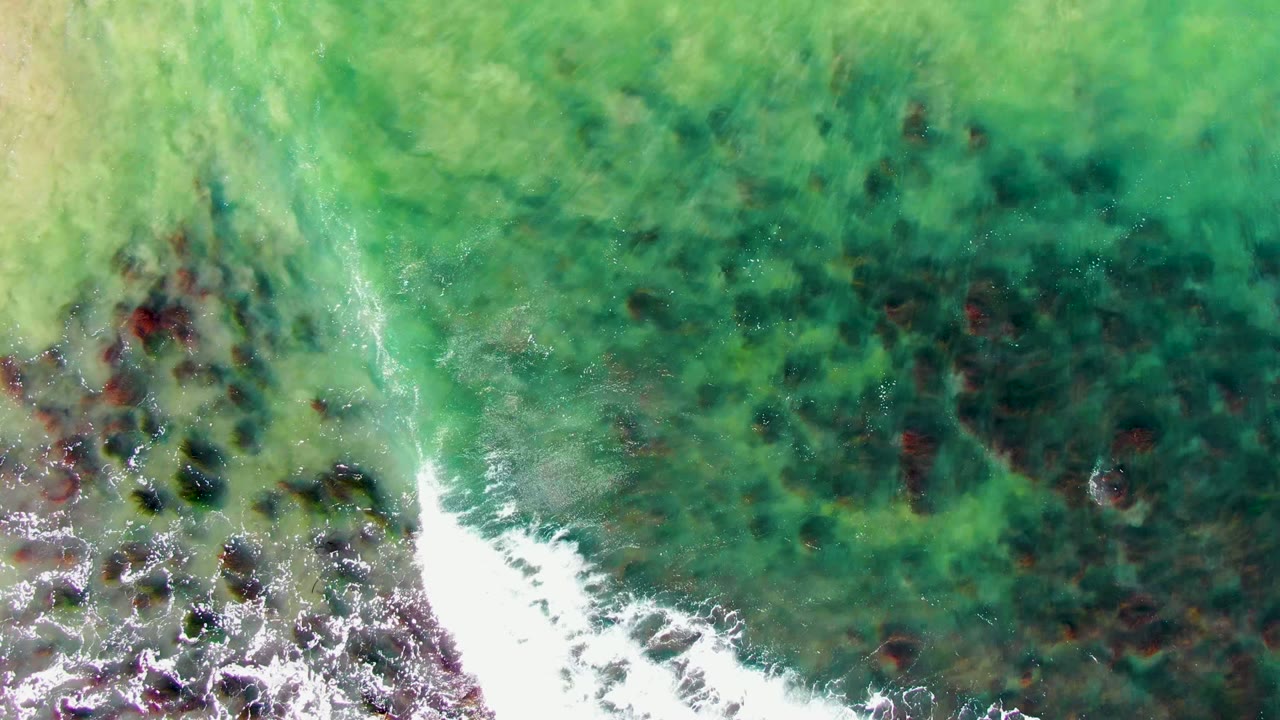 White wave line crossing turquoise water and rocks