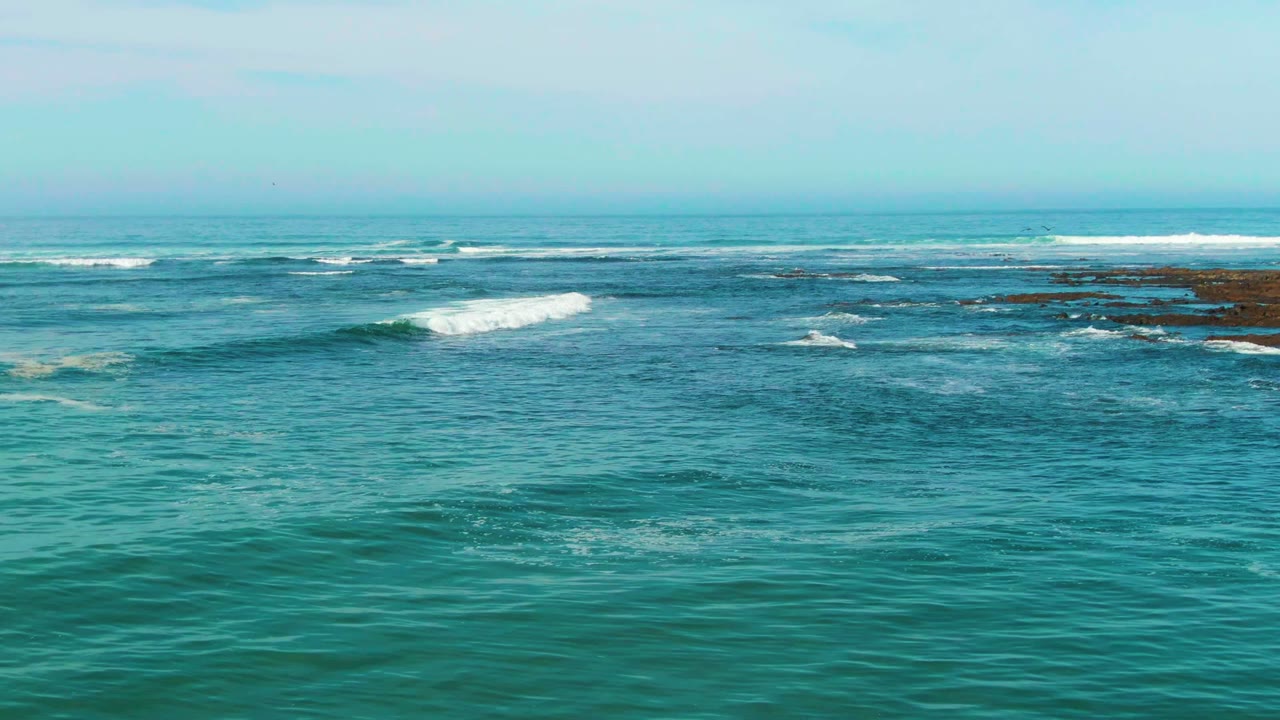 Open turquoise water with surf lines and exposed reef near the horizon
