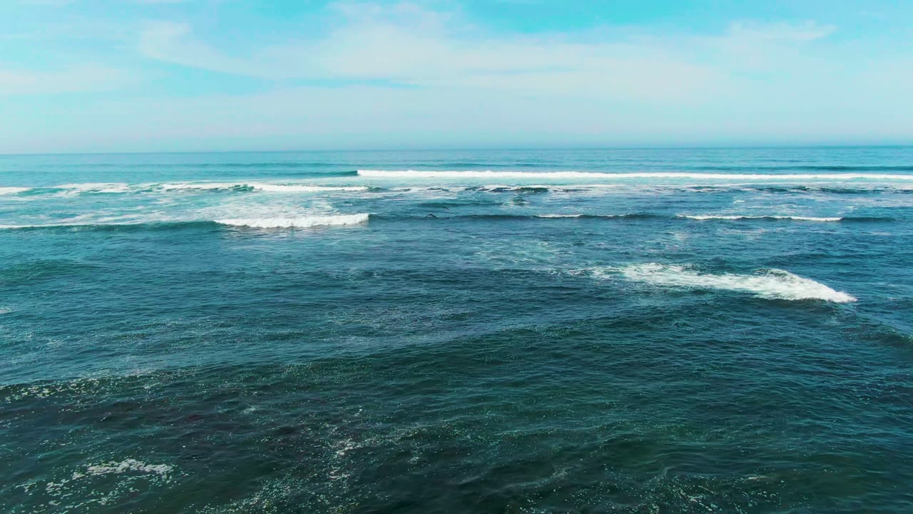 La Bocana ocean surface with scattered foam streaks in the foreground, long white breaker lines in the distance, and no visible people.