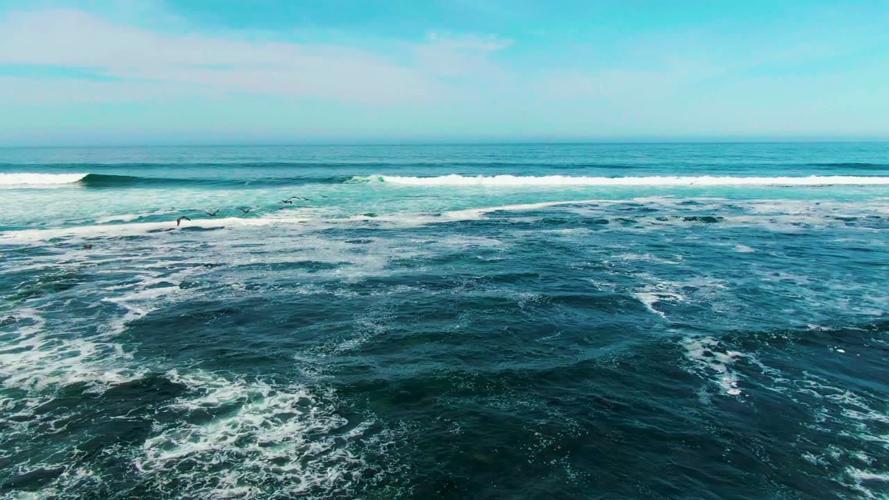 Breaking wave line and swirling foam across blue-green water.