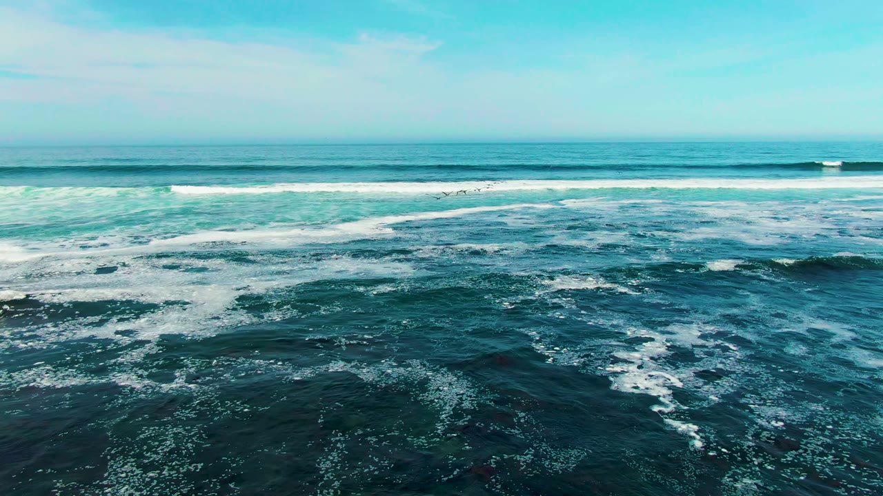 Blue-green ocean waves roll toward the camera at La Bocana, Baja California Sur, with white foam across the water and no visible people.