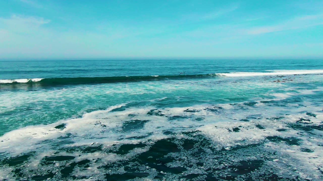 Foamy ocean surface with a breaking wave line near the horizon.
