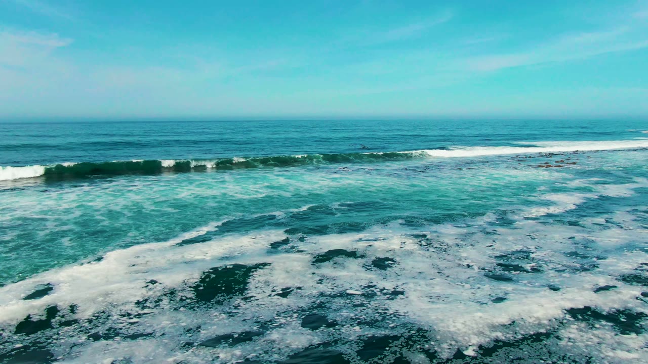 Turquoise coastal water at La Bocana carries bands of white surf across the frame, with open blue sea beyond and no visible people.
