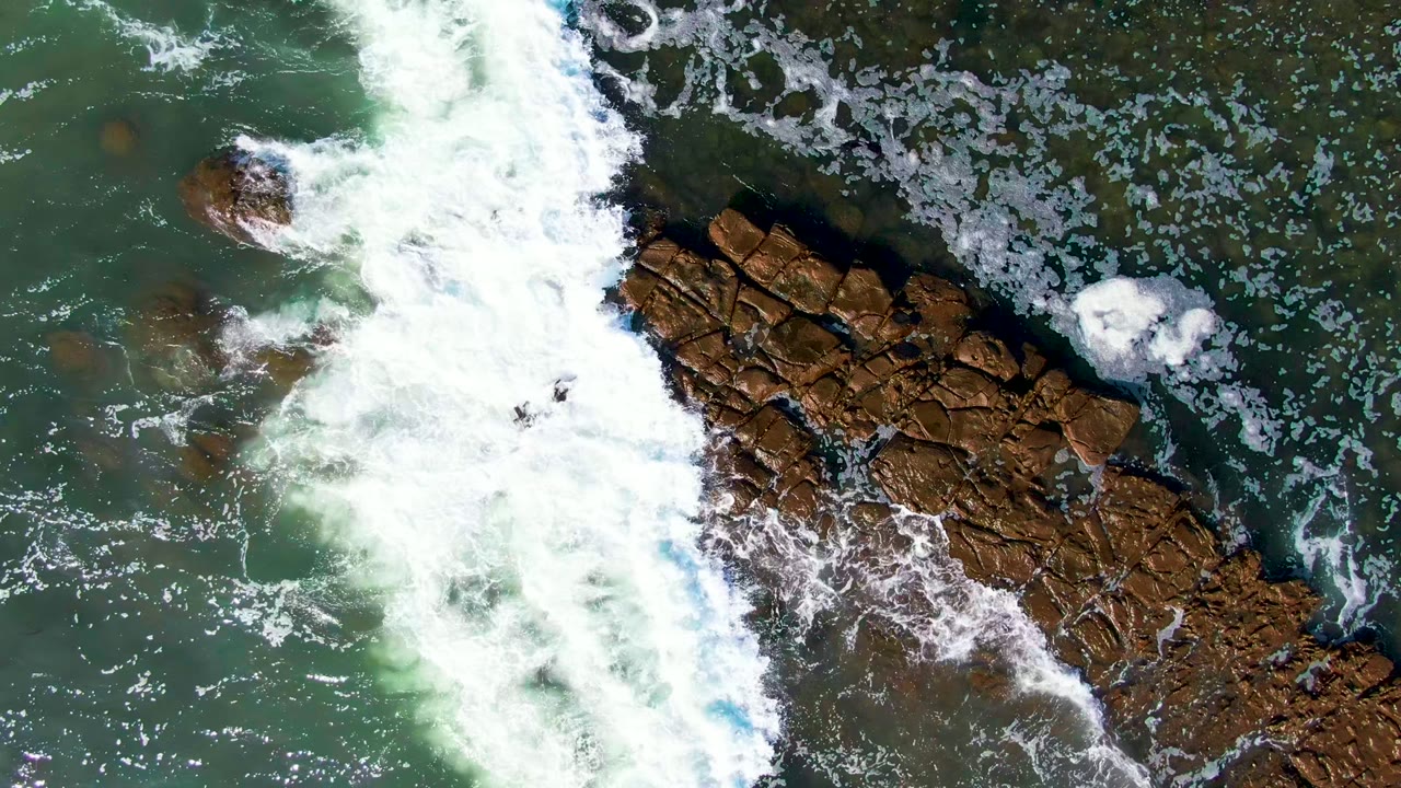 Whitewater spreading beside a diagonal rocky outcrop