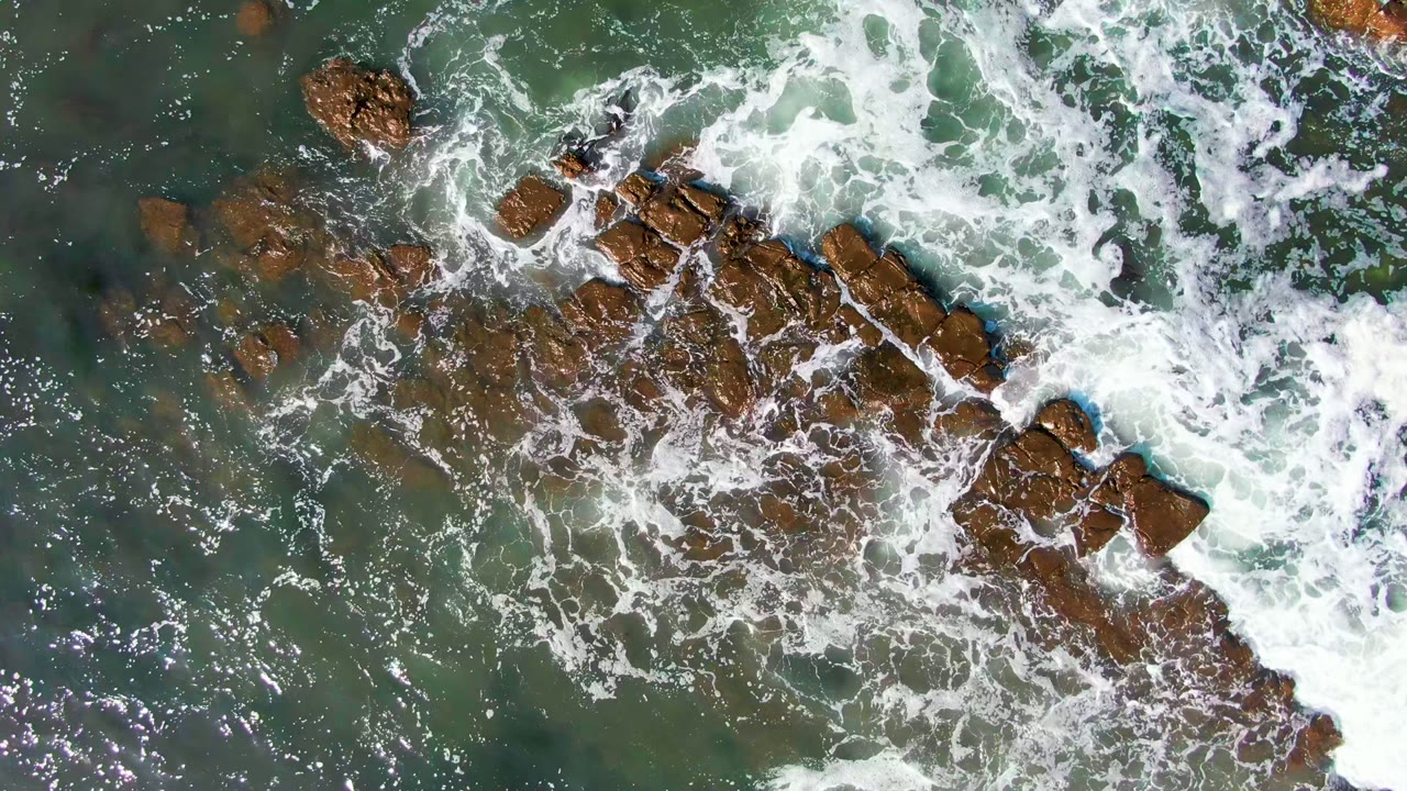 Foam curling around a central rocky outcrop