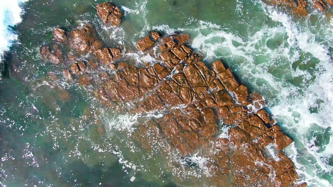 Surf line approaching rocky ocean formation
